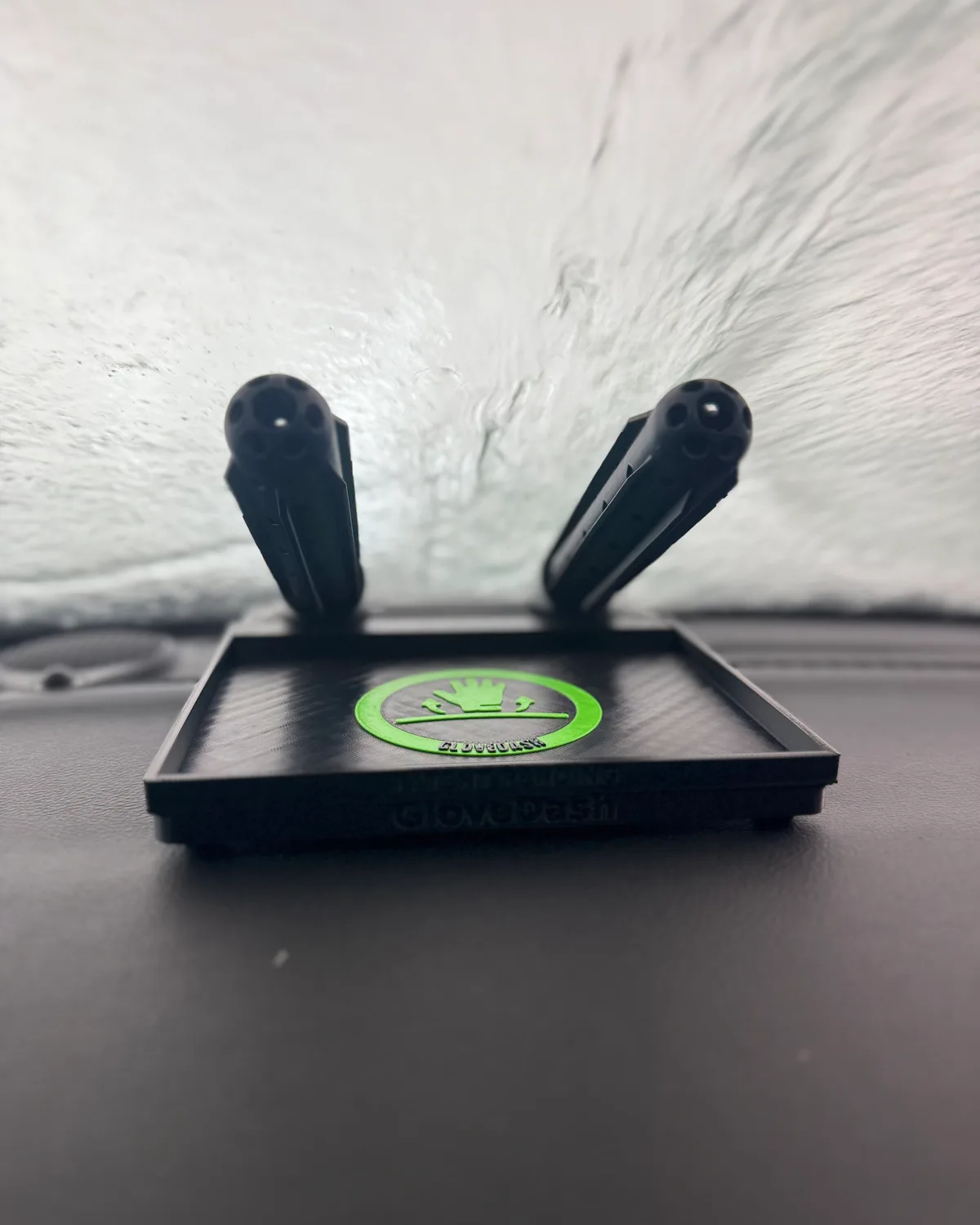 Head on view of a black GloveDash on a dashboard, both tubes angled up with their open vented end hubs facing the camera