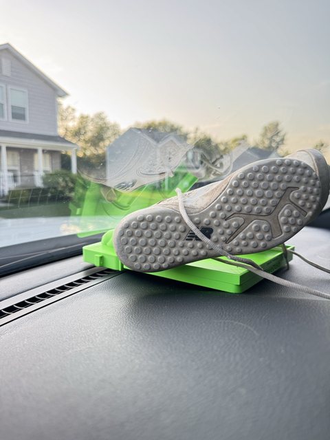 A sneaker drying on a safety green GloveDash on a truck dashboard