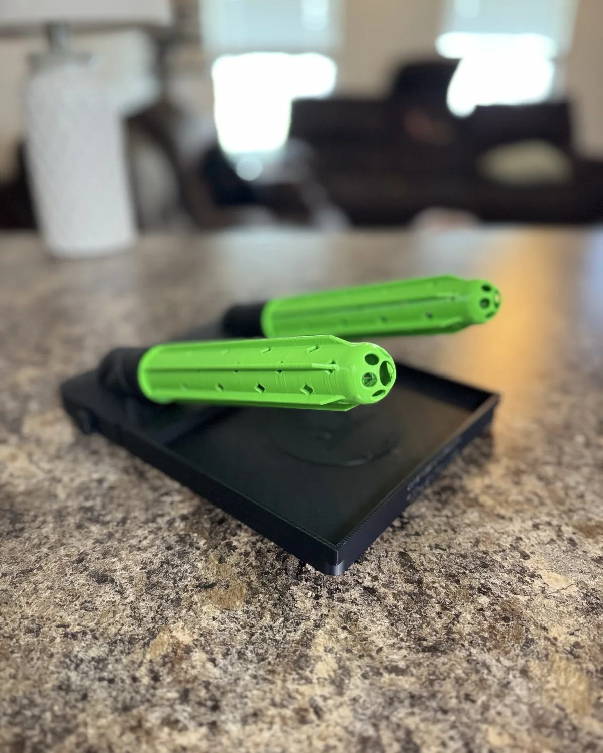 Two safety green tubes resting on a black GloveDash tray, vent slots visible down each tube